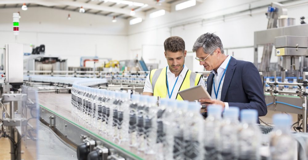 Supervisor and manager watching plastic bottles on conveyor belt